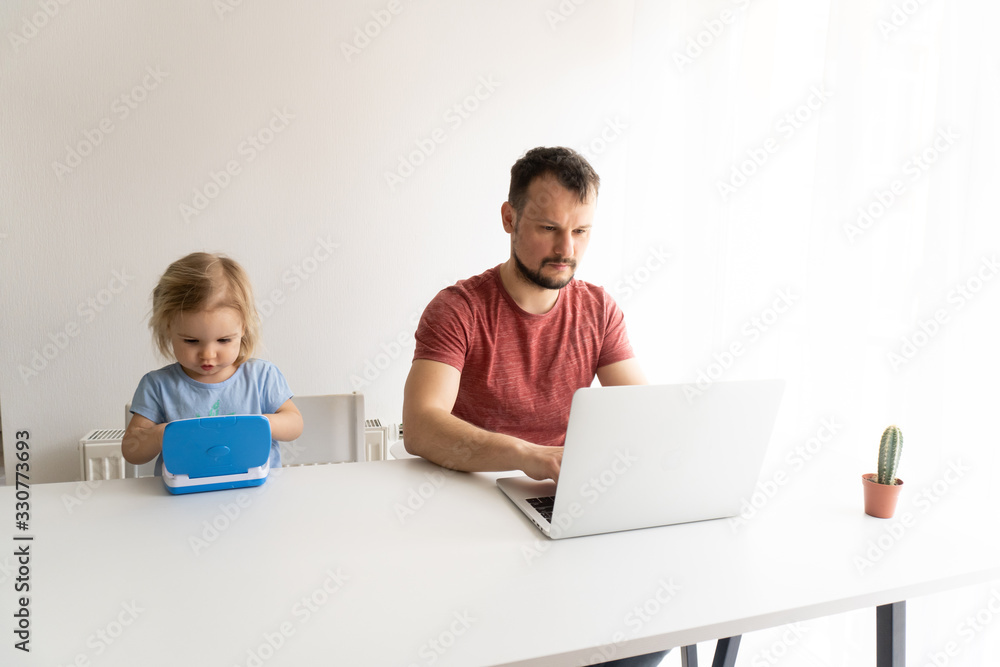 Young man, father should work from home during quarantine time cause of coronavirus. Child at home, kindergarden closed. Baby helps father to work. They work in laptops. White background. Young man, father should work from home during quarantine time cause of coronavirus. Child at home, kindergarden closed. Baby helps father to work. They work in laptops. White background.