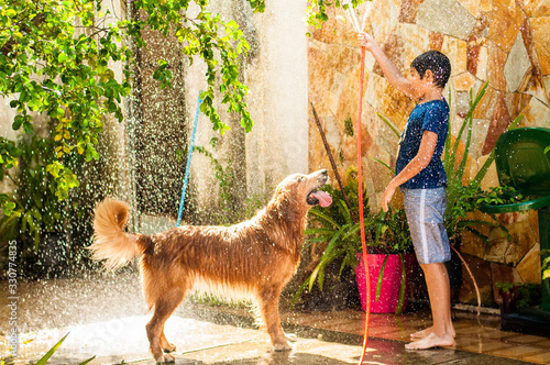 boy playing with his golden retriever dog in tne water