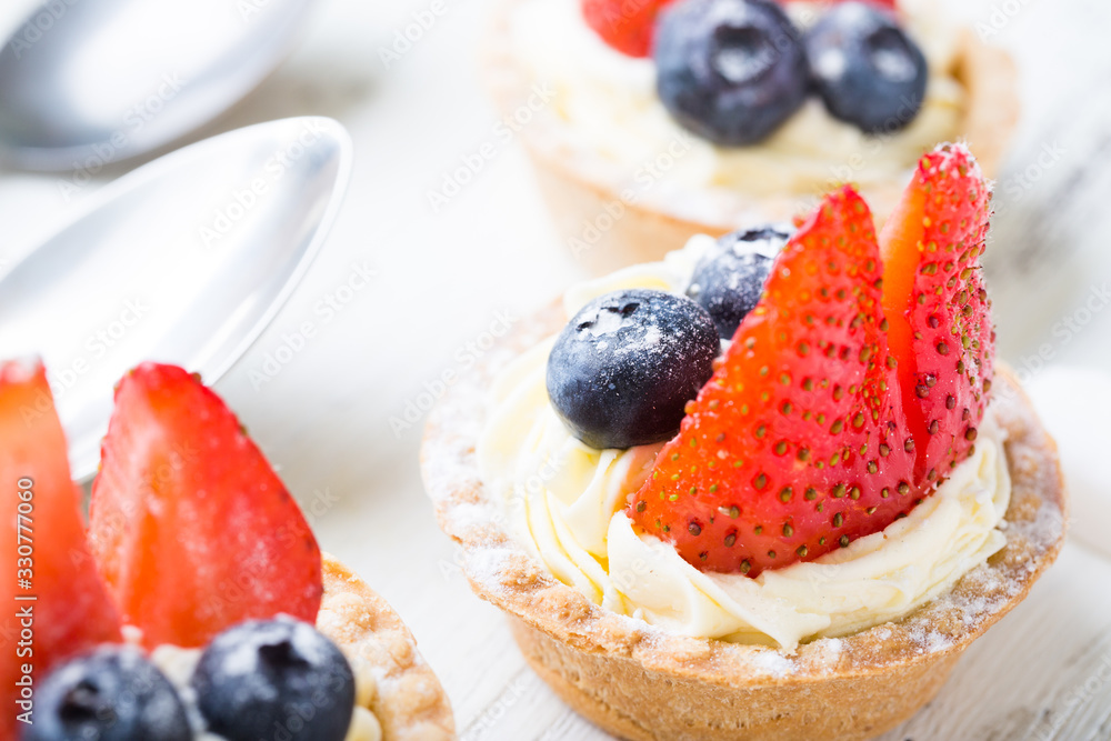 Cakes with fresh berries. Cream tartlet with strawberries and blueberries Cakes with fresh berries. Cream tartlet with strawberries and blueberries