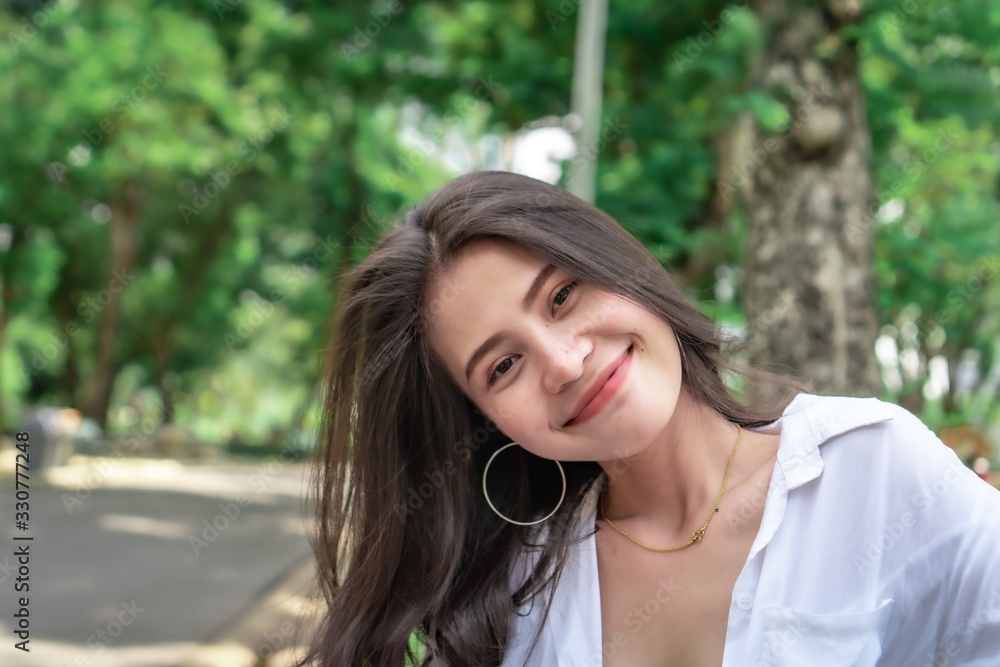 Naklejka premium Beautiful Asian women with long hair wearing a white shirt. White bug hat, jeans showing emotions In the nature park-09.jpg, Asian beautiful woman with yellow skin, long black hair, wearing a white s
