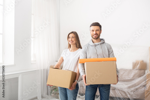 A girl and a guy holding boxes for moving in new apartment
