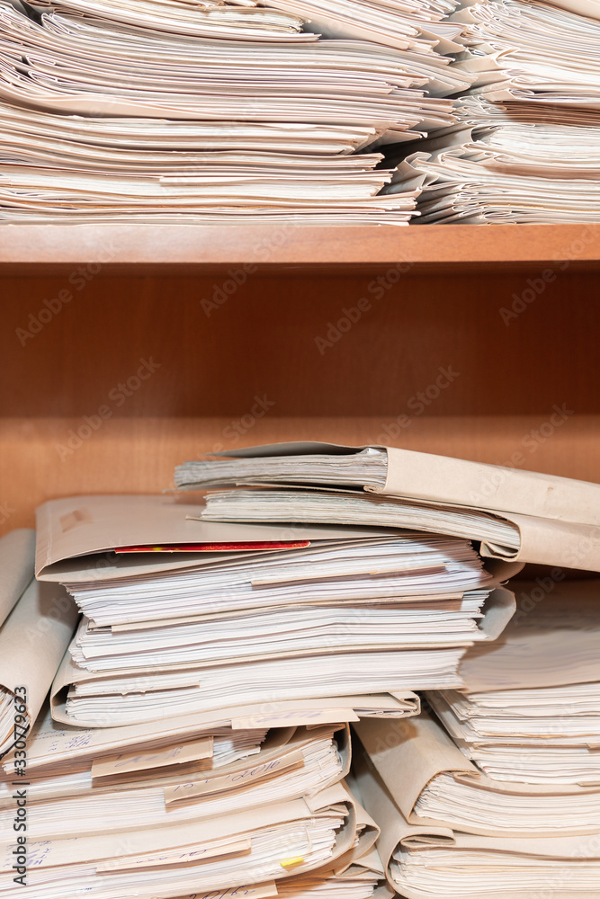 Old paper documents stacked in archive. Documents on the shelves of archive room. Office shelves in the closet full of files Old paper documents stacked in archive. Documents on the shelves of archive room. Office shelves in the closet full of files