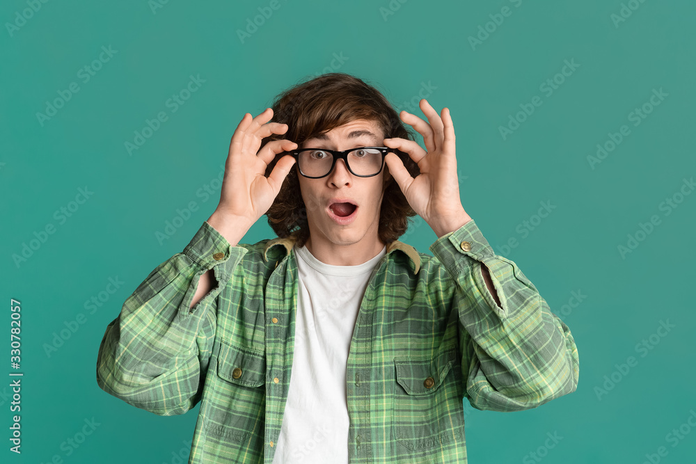 Curly guy with glasses and open mouth feeling shocked on turquoise background Curly guy with glasses and open mouth feeling shocked on turquoise background