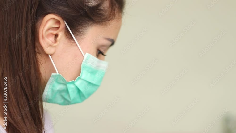 woman putting on surgical mask for corona virus prevention. Close-up of a young woman in a protective medical mask, she looks directly woman putting on surgical mask for corona virus prevention. Close-up of a young woman in a protective medical mask, she looks directly
