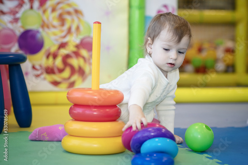 a little girl playing in a kindergarten with plastic rings collects