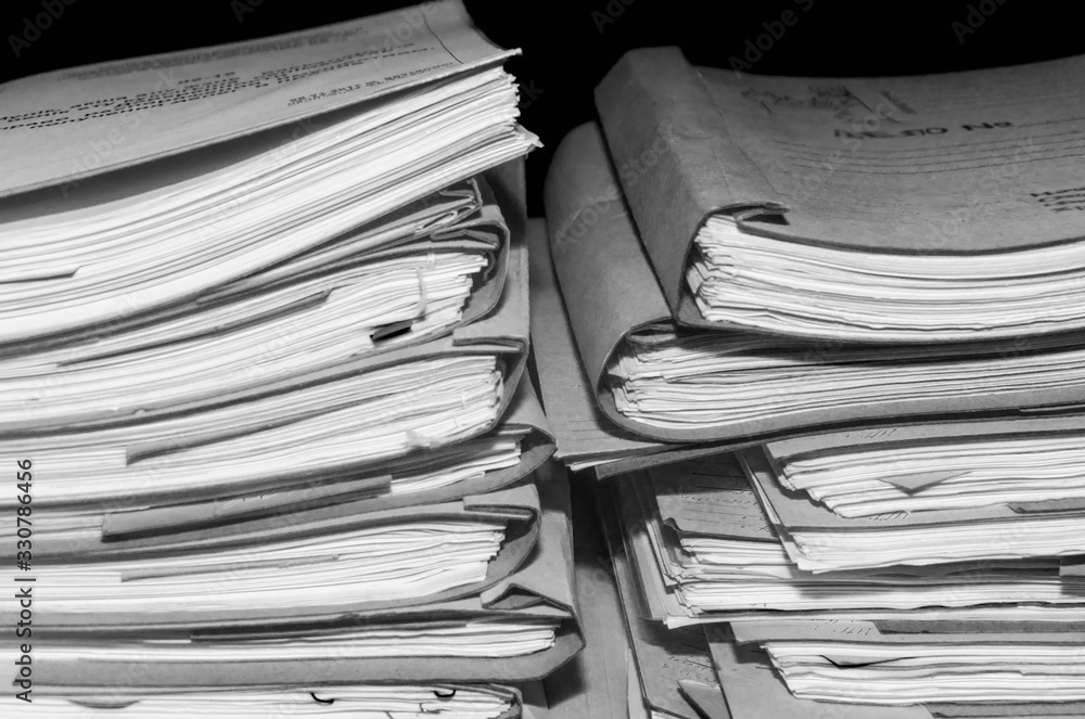 Paper documents stacked in archive. Documents on the shelves of archive room. Office shelves in the closet full of files. black and white photo Paper documents stacked in archive. Documents on the shelves of archive room. Office shelves in the closet full of files. black and white photo