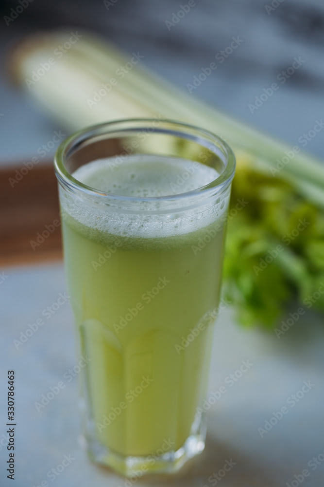 Celery juice in a glass. view over a rustic marble white background. Celery juice in a glass. view over a rustic marble white background.
