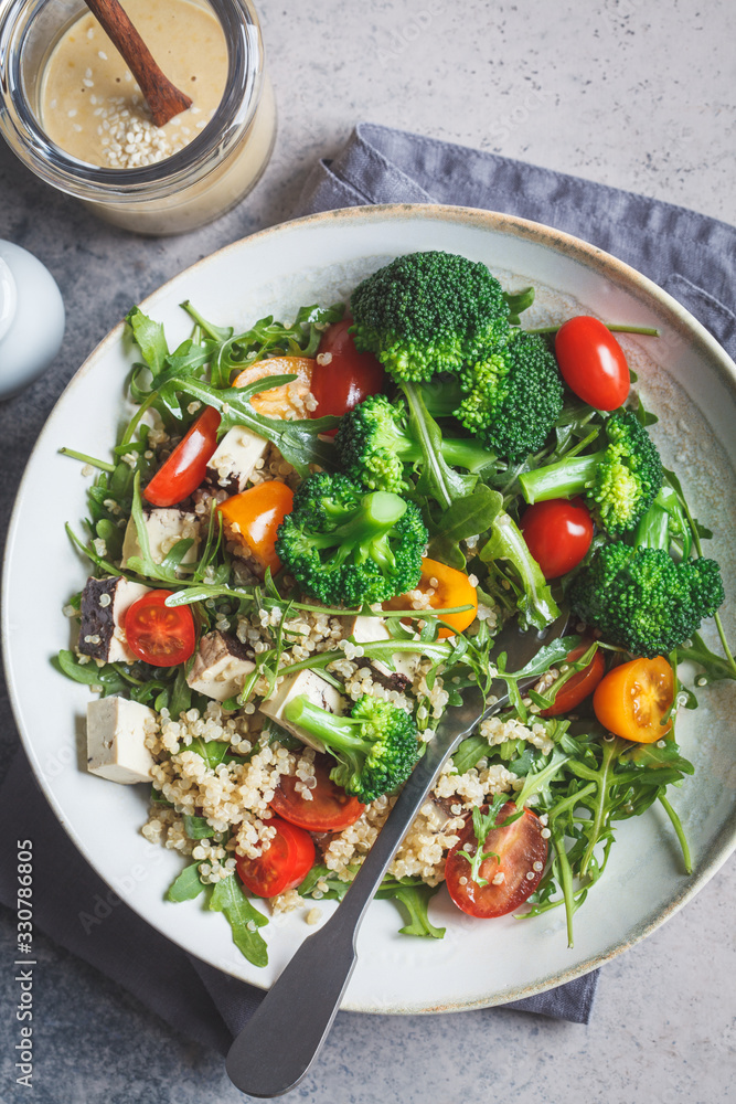 Vegan quinoa salad with tofu, broccoli, tomatoes and nutty dressing. Healthy food concept. Vegan quinoa salad with tofu, broccoli, tomatoes and nutty dressing. Healthy food concept.
