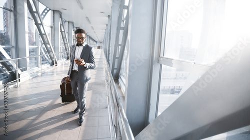 African American Entrepreneur Texting Walking With Suitcase In Airport, Panorama