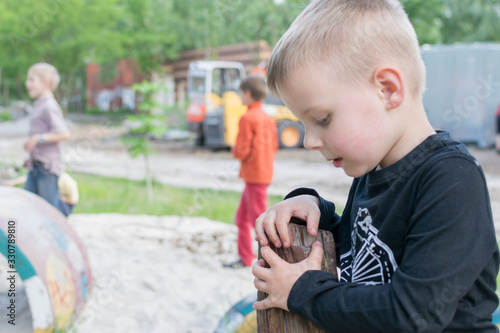 A little boy is playing alone on the playground. The problem of socialization of the child in the team. The concept of autism, closeness, unfriendliness. photo