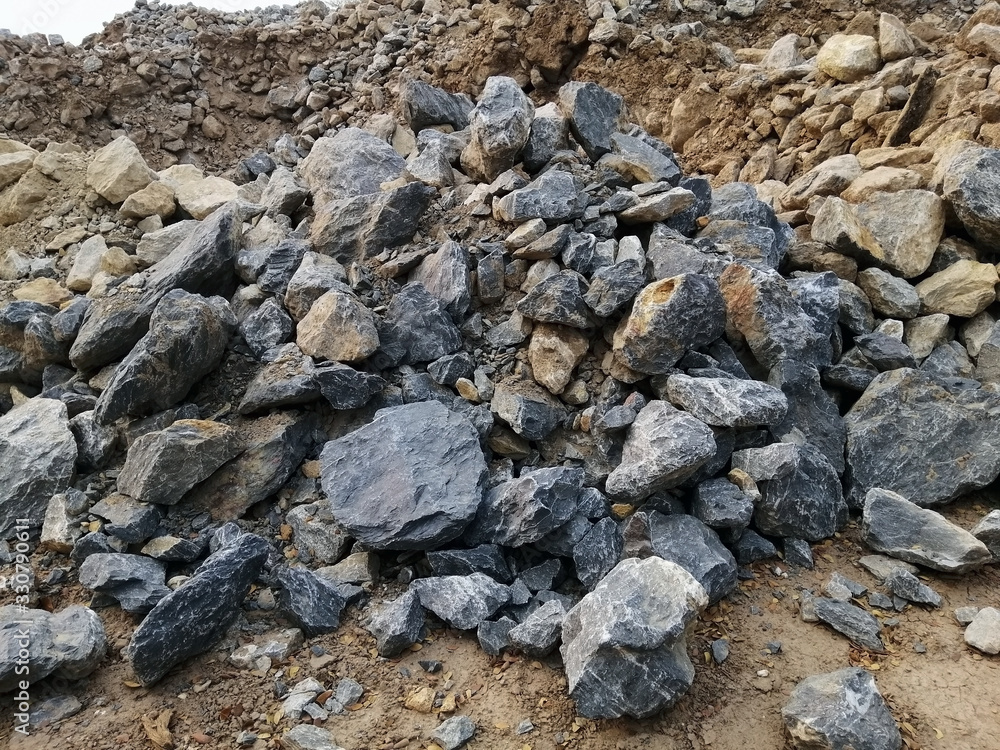 A pile of limestone rock on the ground. Limestone is a sedimentary rock composed primarily of calcium carbonate in the form of the mineral calcite.