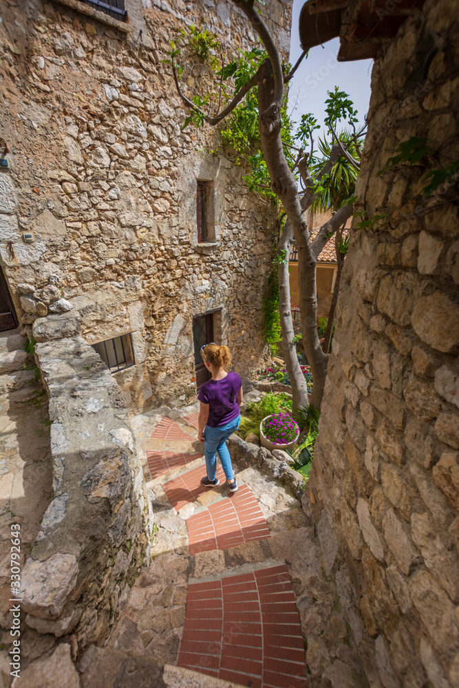 Woman walking stone stairs to house in medieval town, Eze