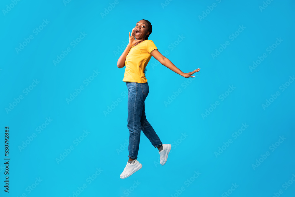 Girl Jumping Shouting Holding Hand Near Mouth Over Blue Background
