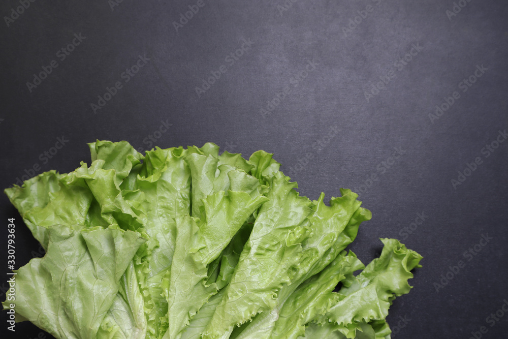 Green lettuce leaves. Vegetables on a black textured background. Green lettuce leaves. Vegetables on a black textured background.