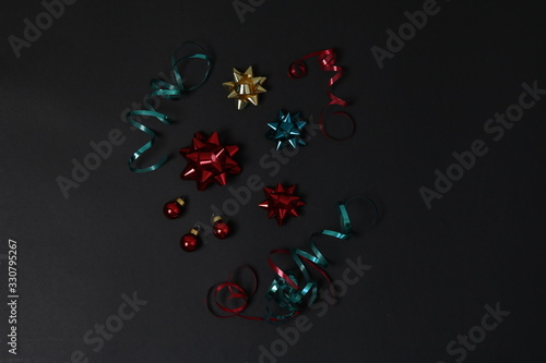 festive decorations view from above. ribbons  gift bows and small red balls on a black background