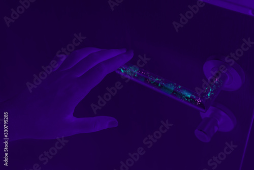 Bacteria, germs and Coronavirus revealed with ultraviolet UV light on dirty door handle surface