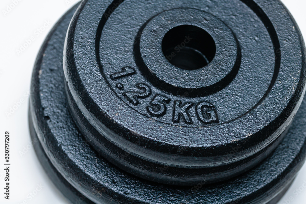 Close-up of four black weight training weights stacked upon each other on a white background. Concept of training, fittness and excercise for a healthy living. Close-up of four black weight training weights stacked upon each other on a white background. Concept of training, fittness and excercise for a healthy living.