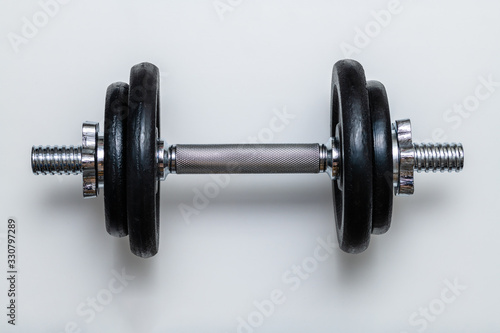 Isolated adjustable dumbbell with black weights and chrome handle on white background. Concept of training, fittness and excercise for a healthy living.
