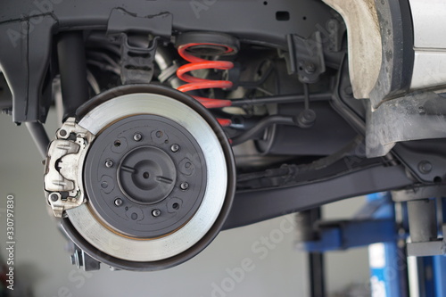 Disc brake of the vehicle for repair, in process of new tire replacement. Car brake repairing in garage.Selective focus disc brake on car, in process of new tire replacement.Close up.