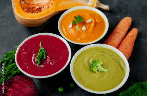 Set of vegetable soups. Broccoli, spinach, green peas soup. Pumpkin and carrot soup. Beetroot and carrot soup on a stone background.