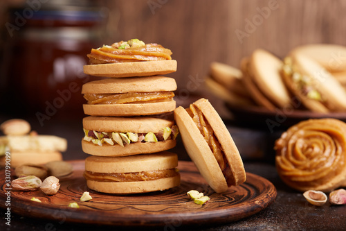 Delicious homemade alfajores cookies with milk caramel cream filling, decorated with pistachio nuts. Sandwich cookies. 