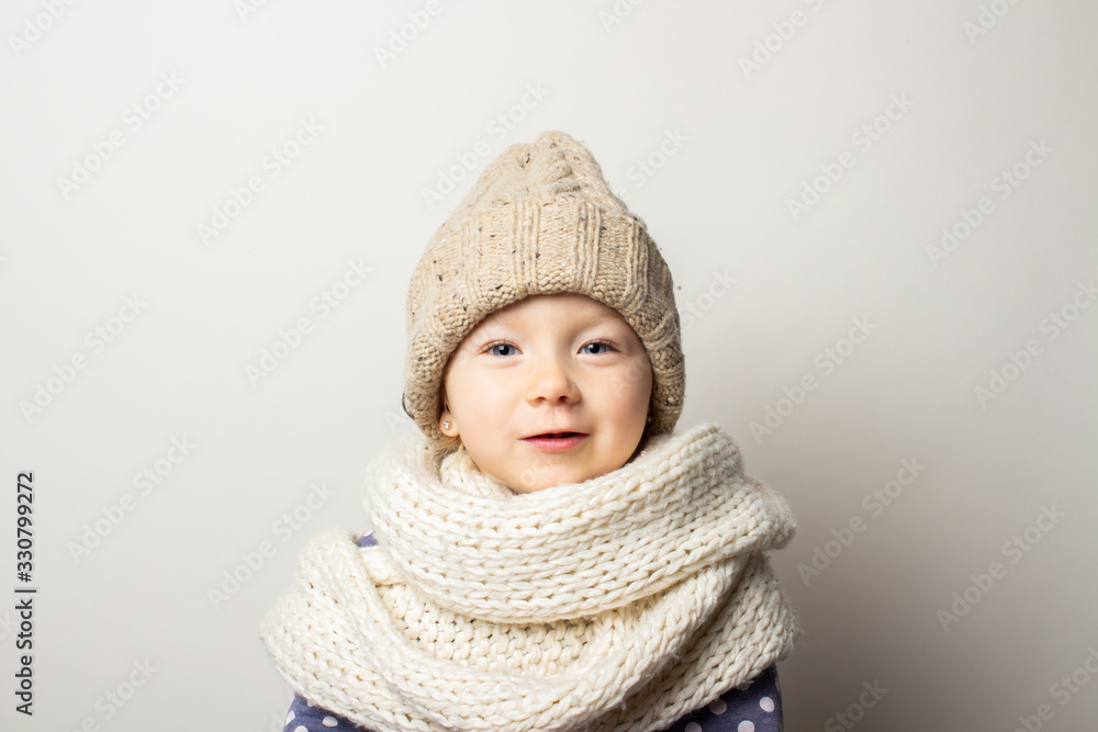 beautiful little baby in a hat on a light background. Concept of children's emotions, winter, shopping