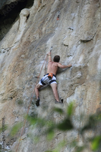 A young man climbing up the natural rock formation 