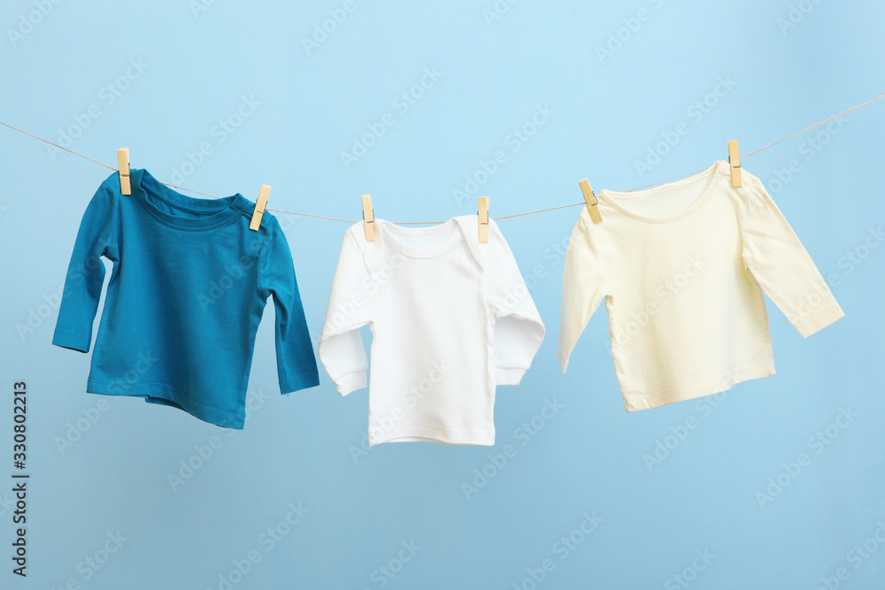 Baby clothes on a rope on a colored background. The concept of washing baby clothes. Baby clothes on a rope on a colored background. The concept of washing baby clothes.