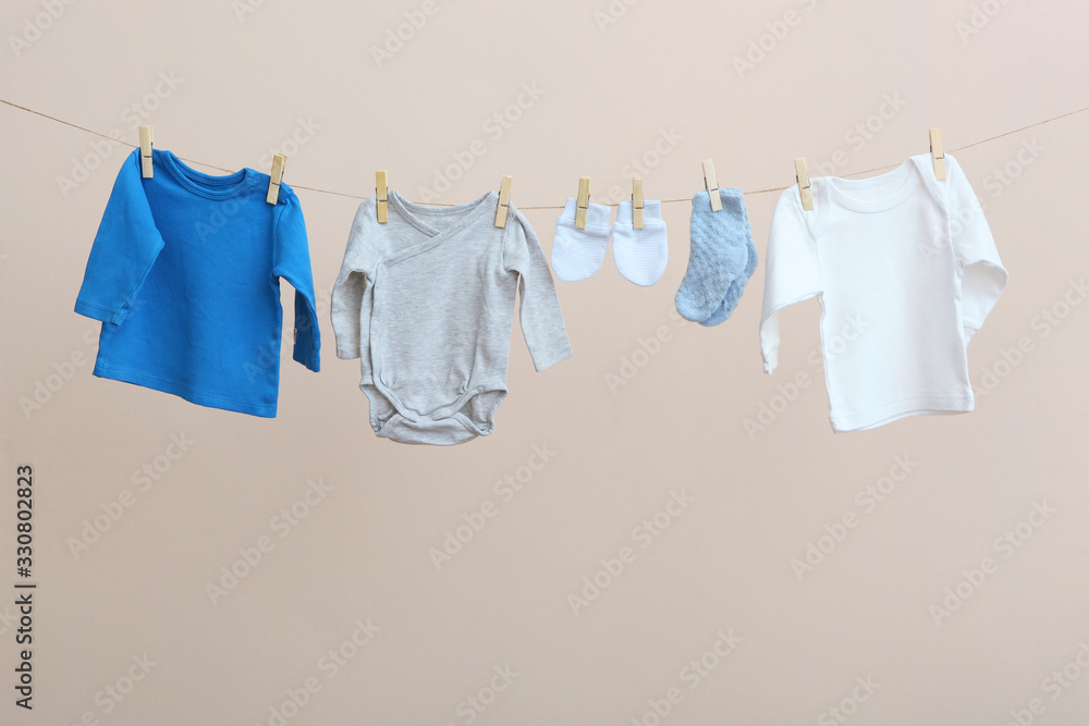 Baby clothes on a rope on a colored background. The concept of washing baby clothes. Baby clothes on a rope on a colored background. The concept of washing baby clothes.
