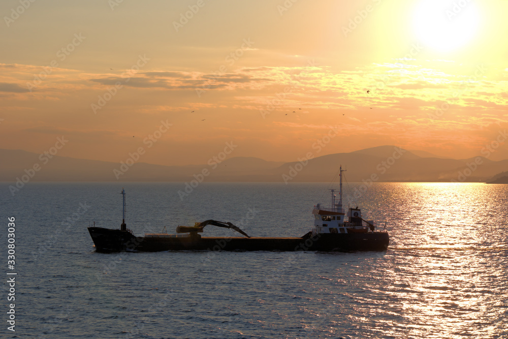 cargo ship, sailing at sunset