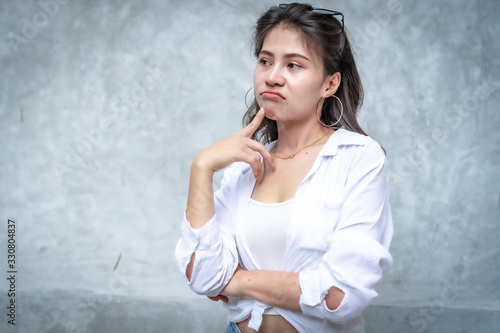 Asian beautiful woman with yellow skin, long black hair, wearing a white shirt, jeans showing her emotions.  Cement wall background-01