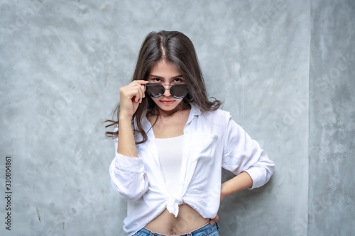 Asian beautiful woman with yellow skin, long black hair, wearing a white shirt, jeans showing her emotions.  Cement wall background-01