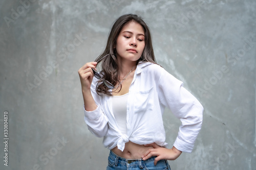 Asian beautiful woman with yellow skin, long black hair, wearing a white shirt, jeans showing her emotions.  Cement wall background-01