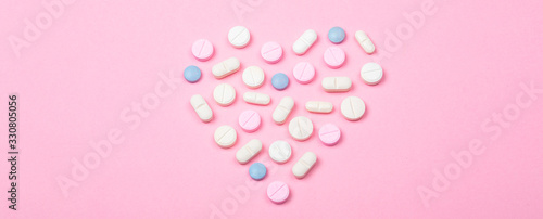 Ensemble de médicaments en forme de coeur sur fond rose