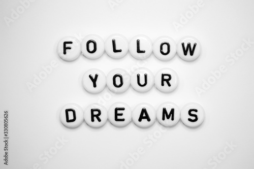 A positive quote FOLLOW YOUR DREAMS written on white cubes, isolated on a white background...