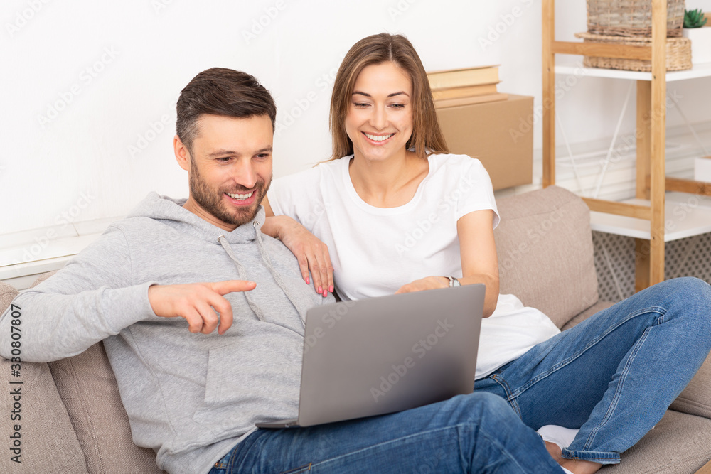 Lovely husband and wife sit in new apartment with laptop Lovely husband and wife sit in new apartment with laptop
