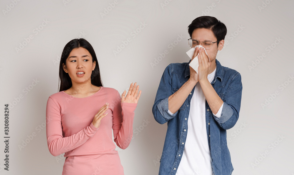 Coronavirus Anxiety. Disgusted asian girl keeping distance with her sick boyfriend Coronavirus Anxiety. Disgusted asian girl keeping distance with her sick boyfriend