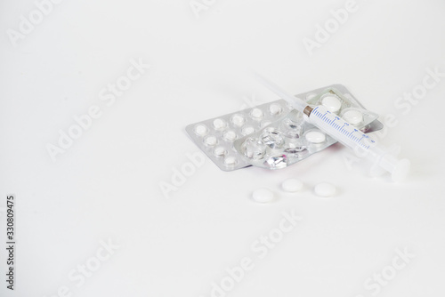 Tablets, capsules, medications, a thermometer and a syringe lie on a white background. Medical means of fighting viruses, coronavirus, covid 19