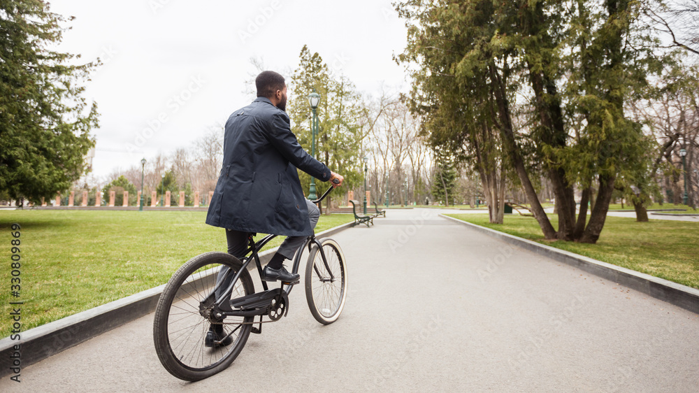 Handsome afro businessman riding his bike in park
