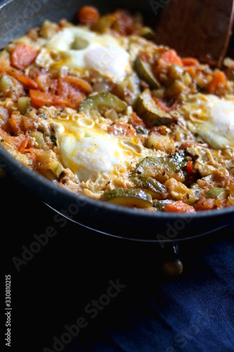Shakshuka in a pan, with seasonal vegetables and eggs. Selective focus.