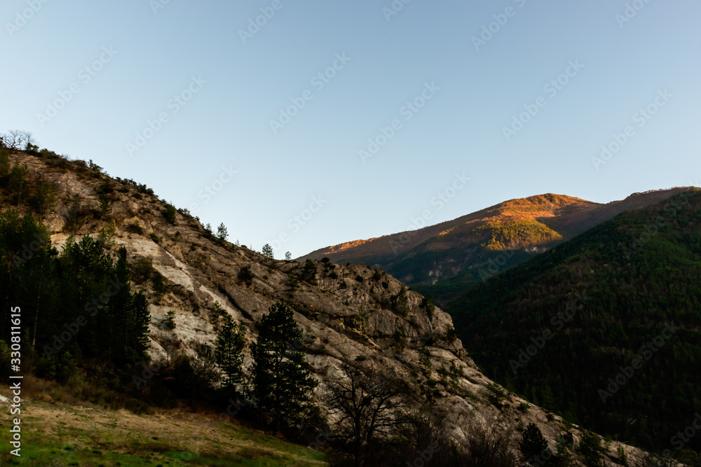 A mountain range illuminated by warm sunlight during the early sunset (French Alps)