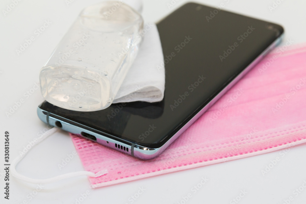 Close up of set of things necessary to protect against a virus covid-19, Coronavirus . Smartphone, pink medical mask, antibacterial agent. Close up of set of things necessary to protect against a virus covid-19, Coronavirus . Smartphone, pink medical mask, antibacterial agent.