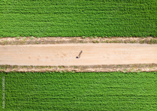 the shadow of a man walking by the field by drone