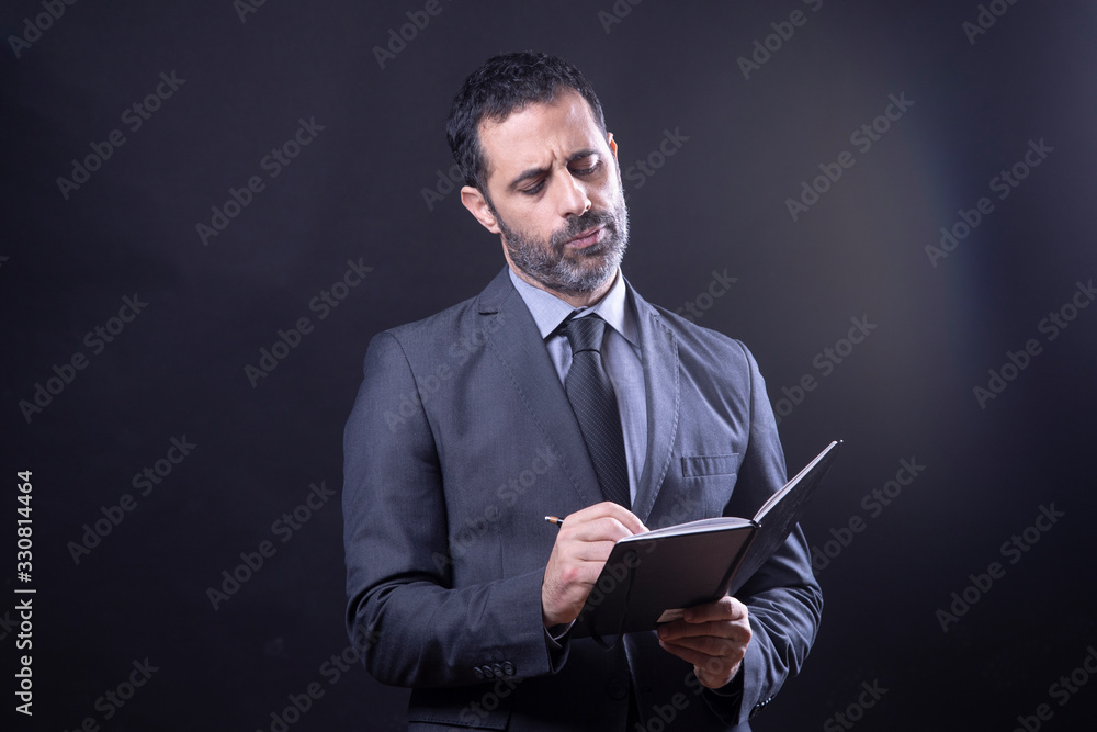 Uomo vestito in abito, segna degli appunti in un agenda - Isolato su sfondo nero Uomo vestito in abito, segna degli appunti in un agenda - Isolato su sfondo nero