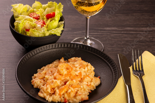 plate of shrimp risotto, lettuce salad and cherry tomatoes and a glass of white wine