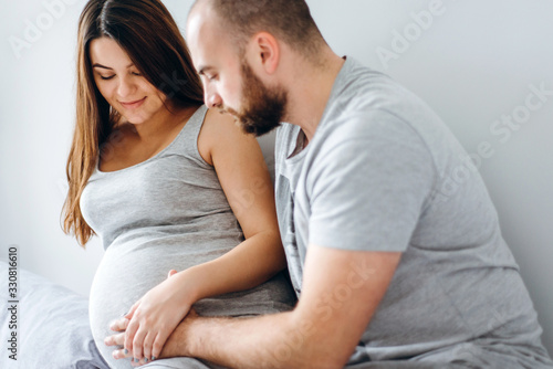 Pregnancy. Young couple waiting for baby. Wonderful expectant parents cuddle in their apartment awaiting birth