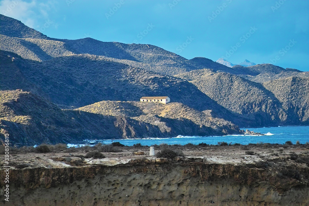 ocky spanish coast line in the sun with building on top of a hill