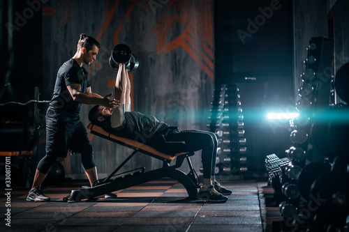 Foto young man has workout with personal trainer in modern gym