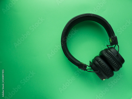 Classic black wireless headphones on colored paper background. Retro style. 80s. Pop culture. Top view.