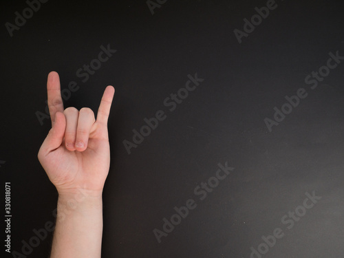 Female hand shows a gesture of rock horns on black background